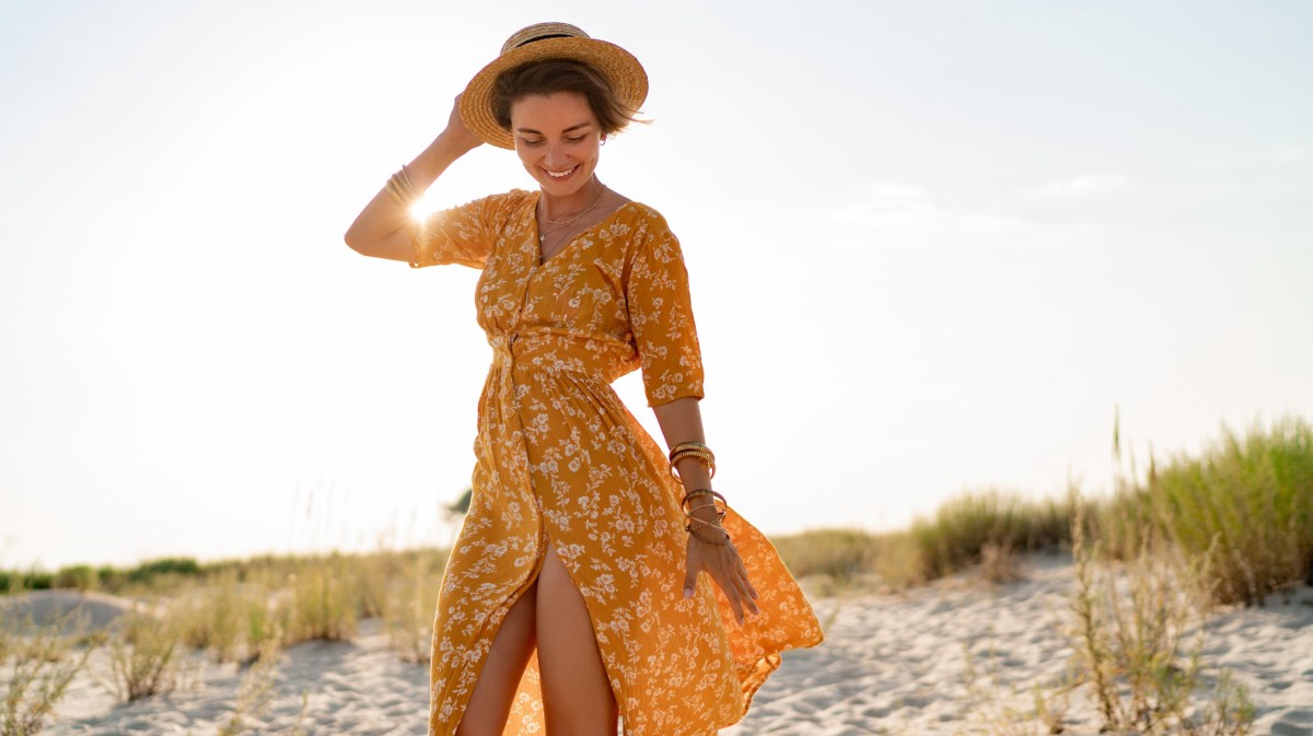 Frau in orangem Kleid am Strand.