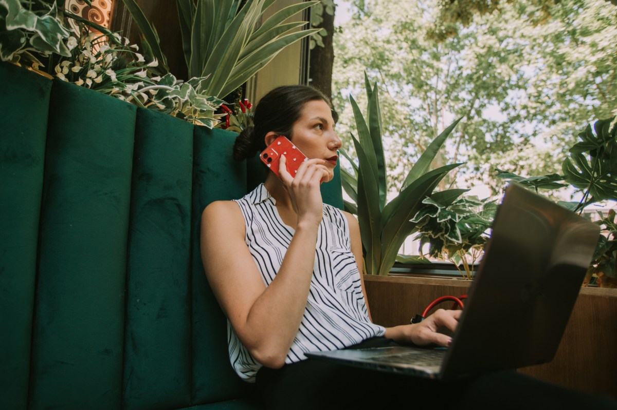 Business-Woman sitzt am Laptop und telefoniert.