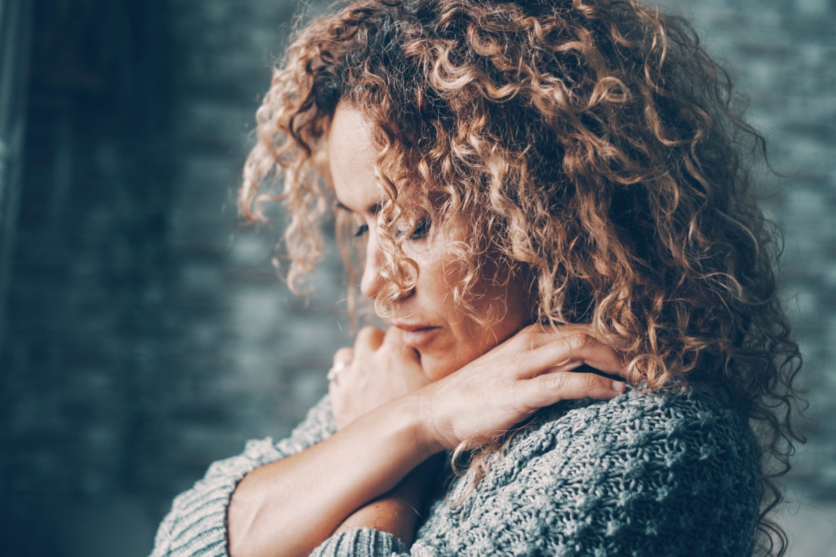 Frau ist nachdenklich und umarmt sich.