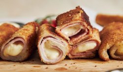 Toast-Röllchen mit Schinken und Käse auf einem Holzbrett.