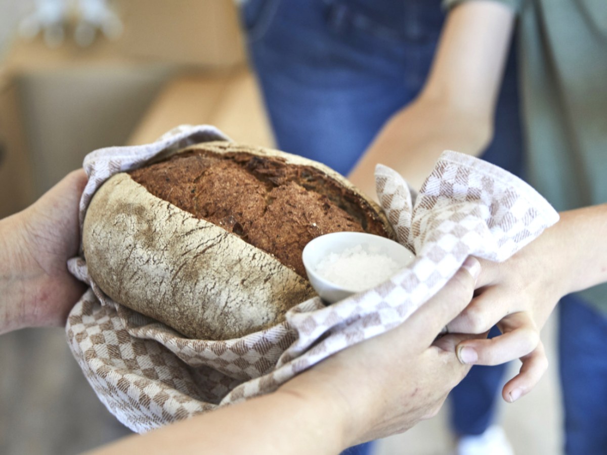 Person &uuml;berreicht Paar Brot und Salz zum Einzug.