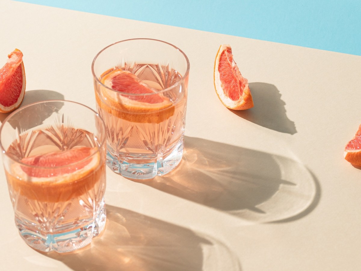 Zwei Gläser mit dem Pink Spritz auf hellem Untergrund mit hellblauem Hintergrund.