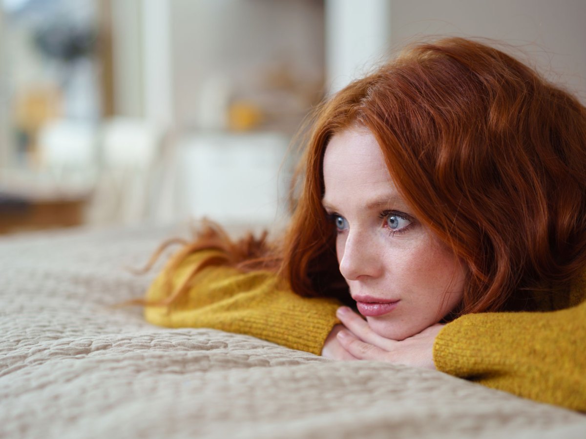 Frau mit roten Haaren liegt auf dem Bett