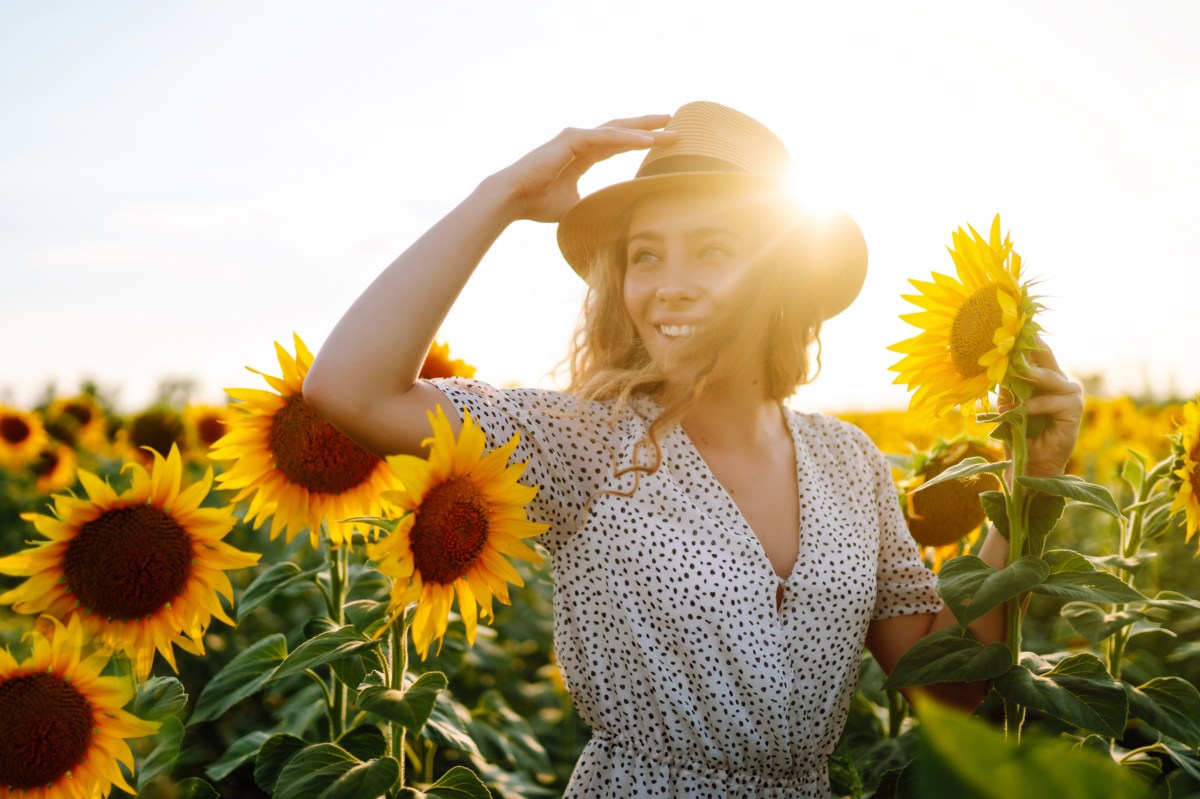 Frau auf einem Feld voller Sonnenblumen.