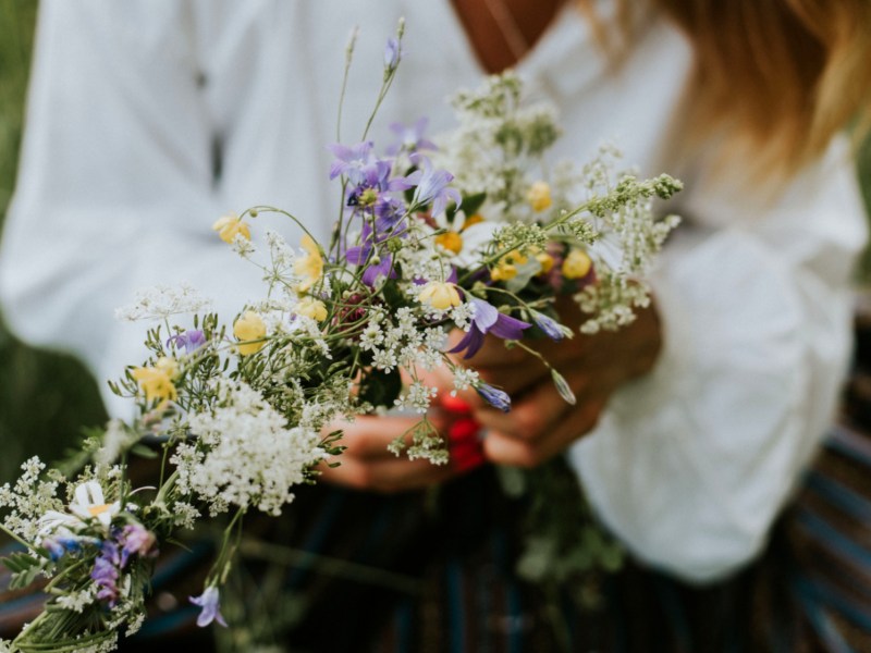 Frau mit weißer Blume hat Sommerblumen in der HAnd