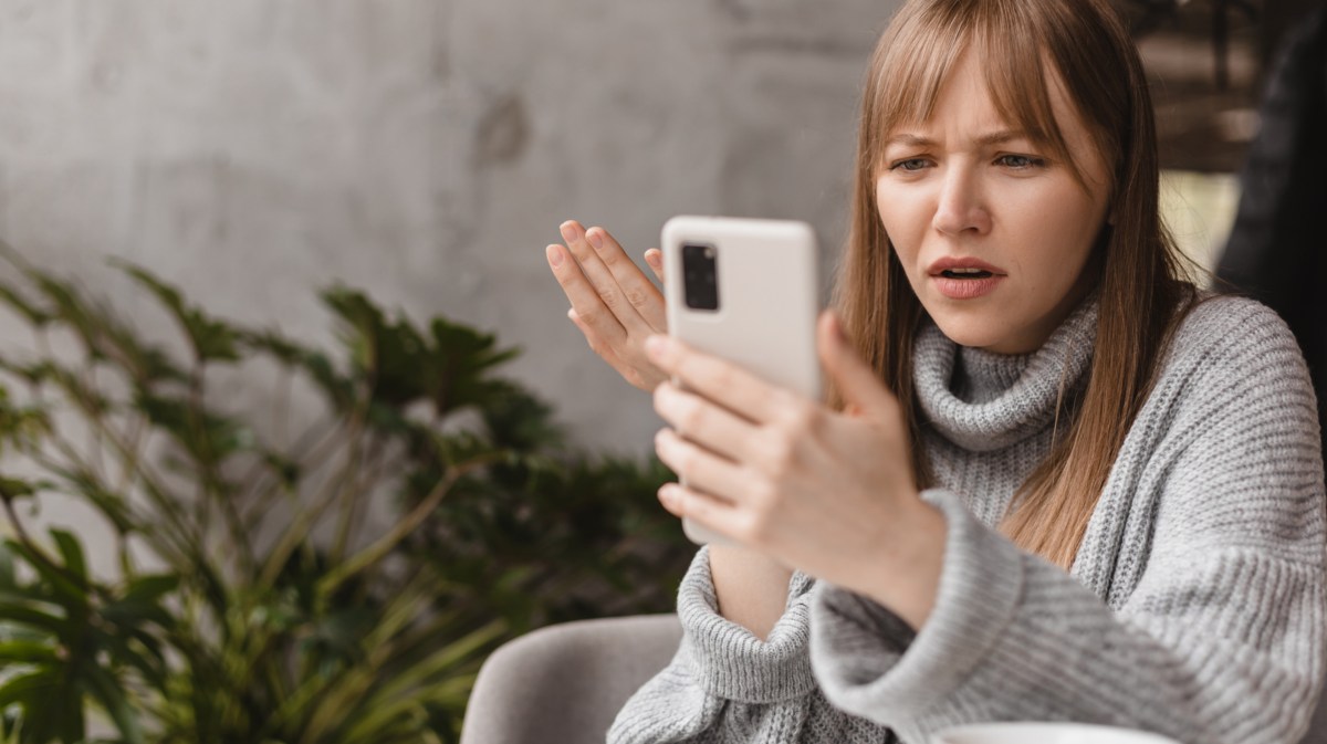 Frau schaut wütend auf ihr Handy.