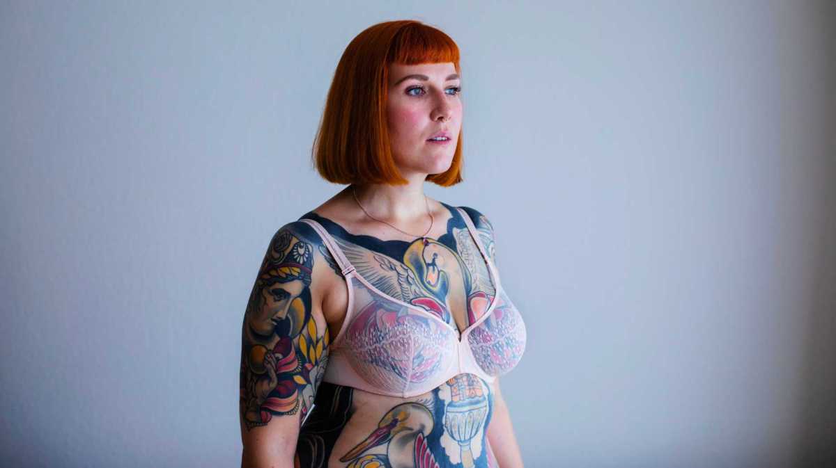 Rothaarige Frau mit Ganzkörpertattoos.