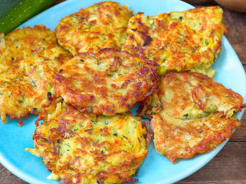 Rösti aus Kartoffeln und Zucchini auf einem blauen Teller.