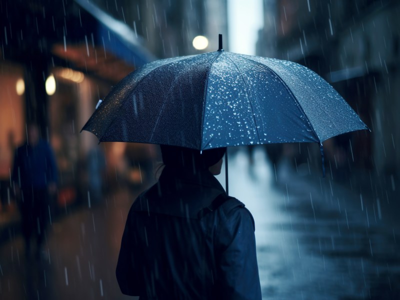 Person mit Regenschirm in dunkler Straße