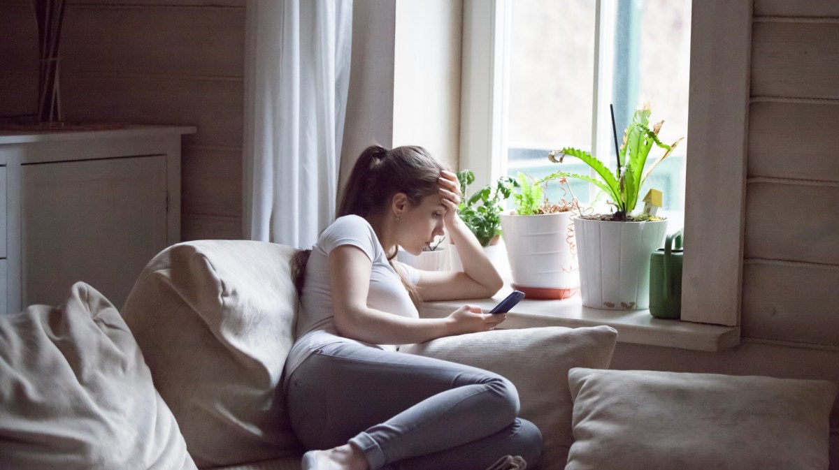 Frau auf einem Sofa mit Handy in der Hand