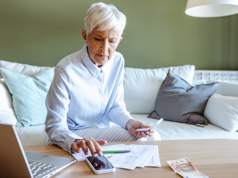 Ältere Frau mit weißen kurzen Haaren berechnet Finanzen