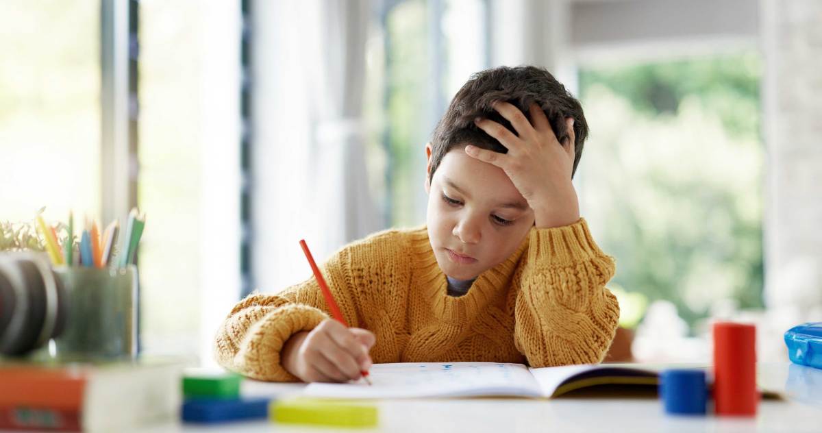 Junge sitzt nachdenklich und konzentriert an seinen Schulaufgaben.