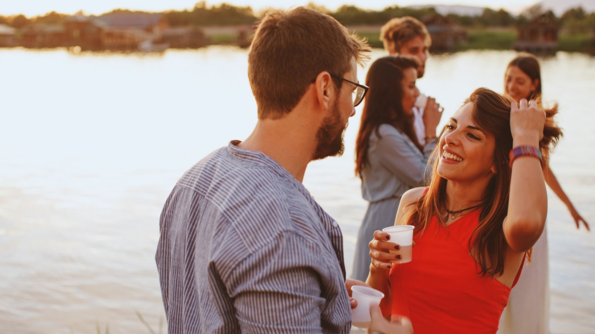 Frau und Mann auf einem Steg, die sich anlachen und miteinander flirten