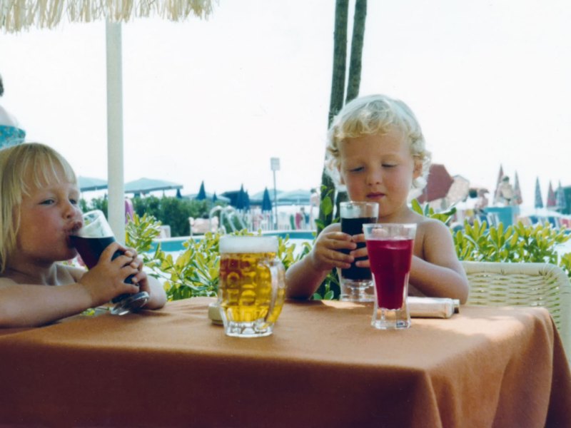 Ein Bild von zwei Kindern an einem Tisch mit Cola Gläsern, geschossen in den 80er Jahren.