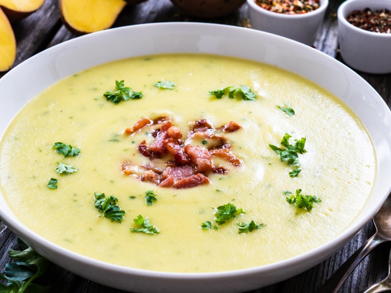 Kartoffelsuppe in weißer Schale mit Speck und Petersilie.