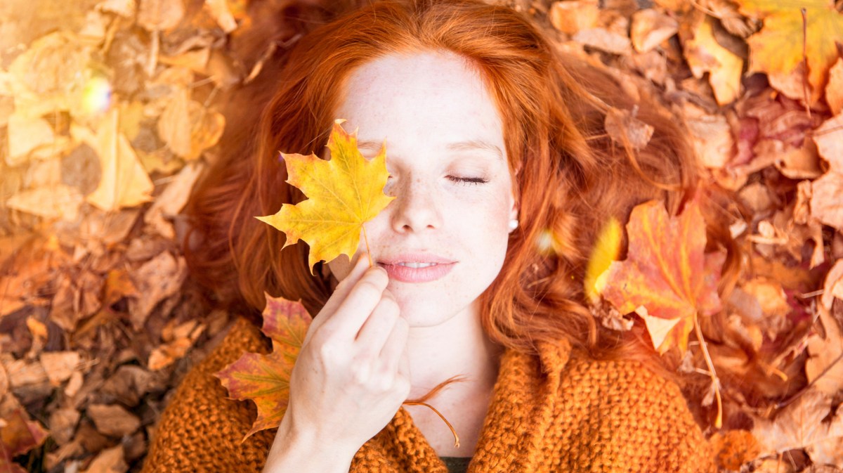 Frau liegt in orangenen Herbstblätter.