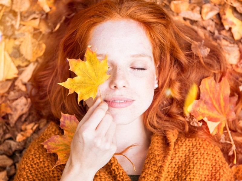 Frau liegt in orangenen Herbstblätter.