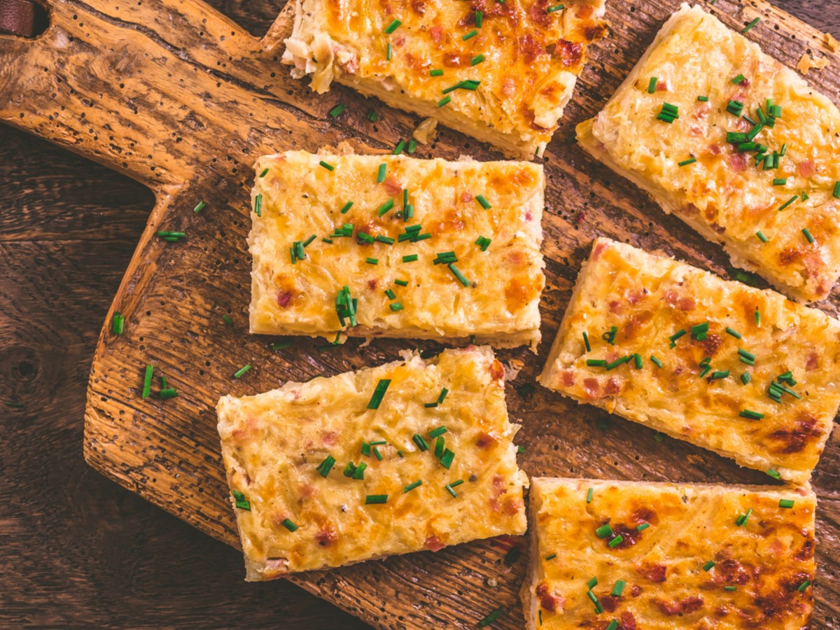 Zwiebelkuchen auf einem Holzbrett.