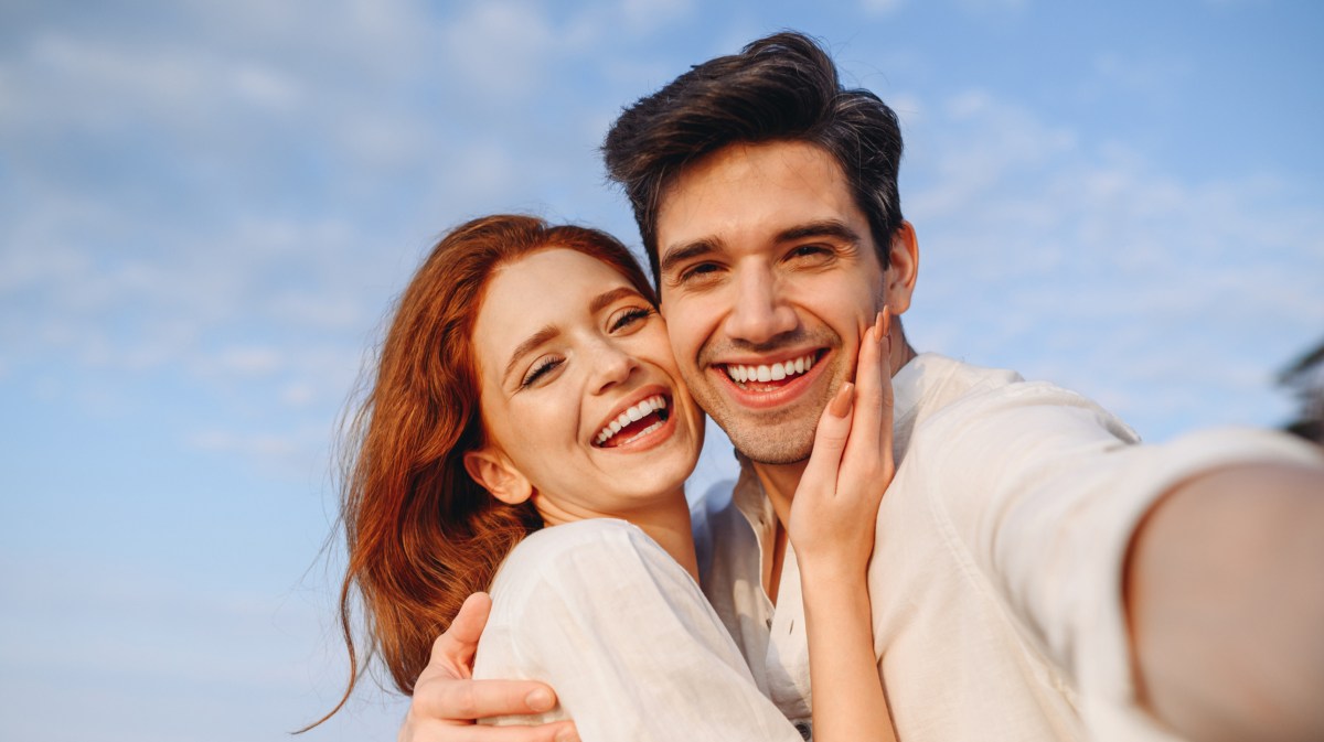 Mann und Frau, die beide in die Kamera lachen und ein Selfie machen