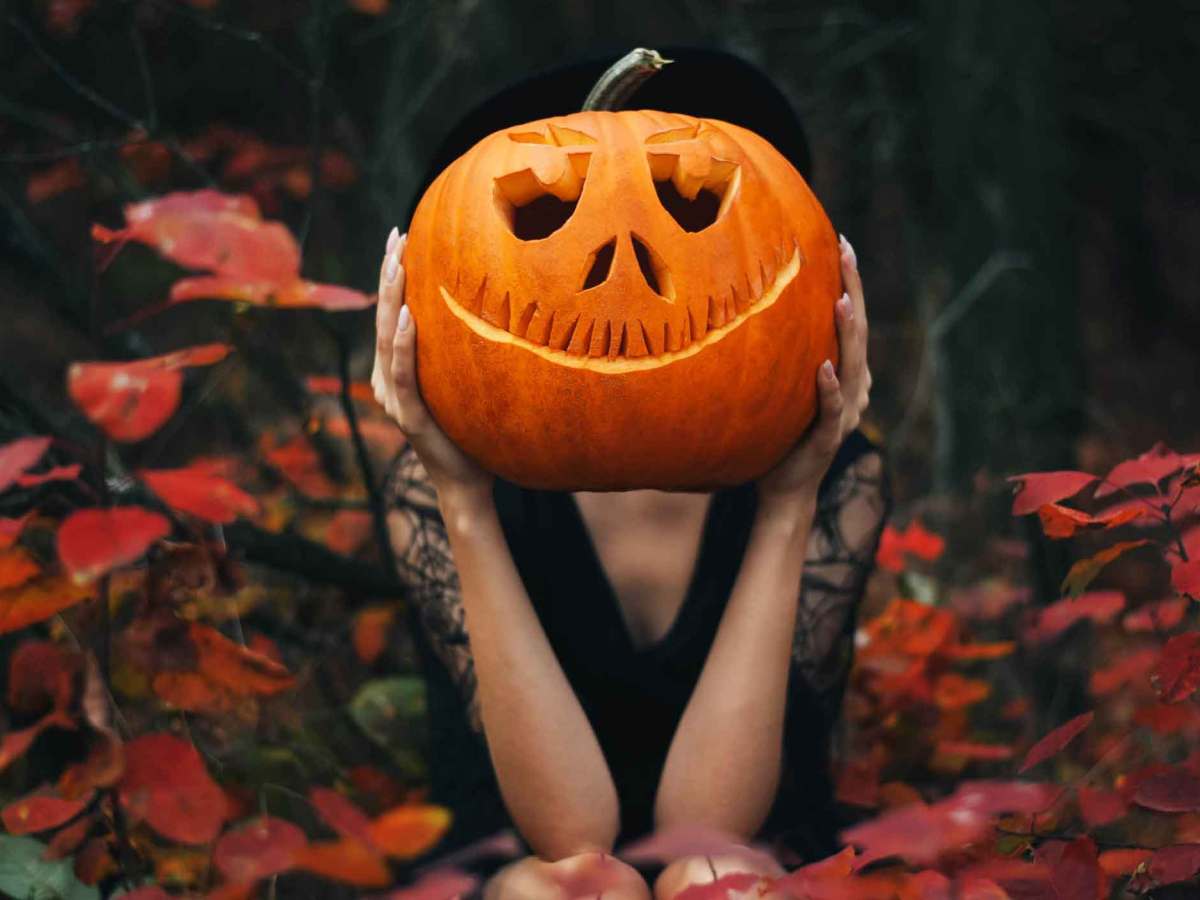 Frau hebt einen K&uuml;rbis in die Luft.