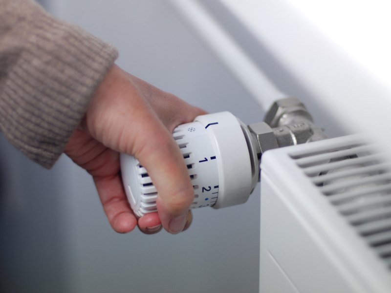 Person dreht an Heizung