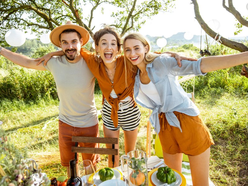 Zwei Frauen in ein Mann lachen ausgelassen vor Wiese