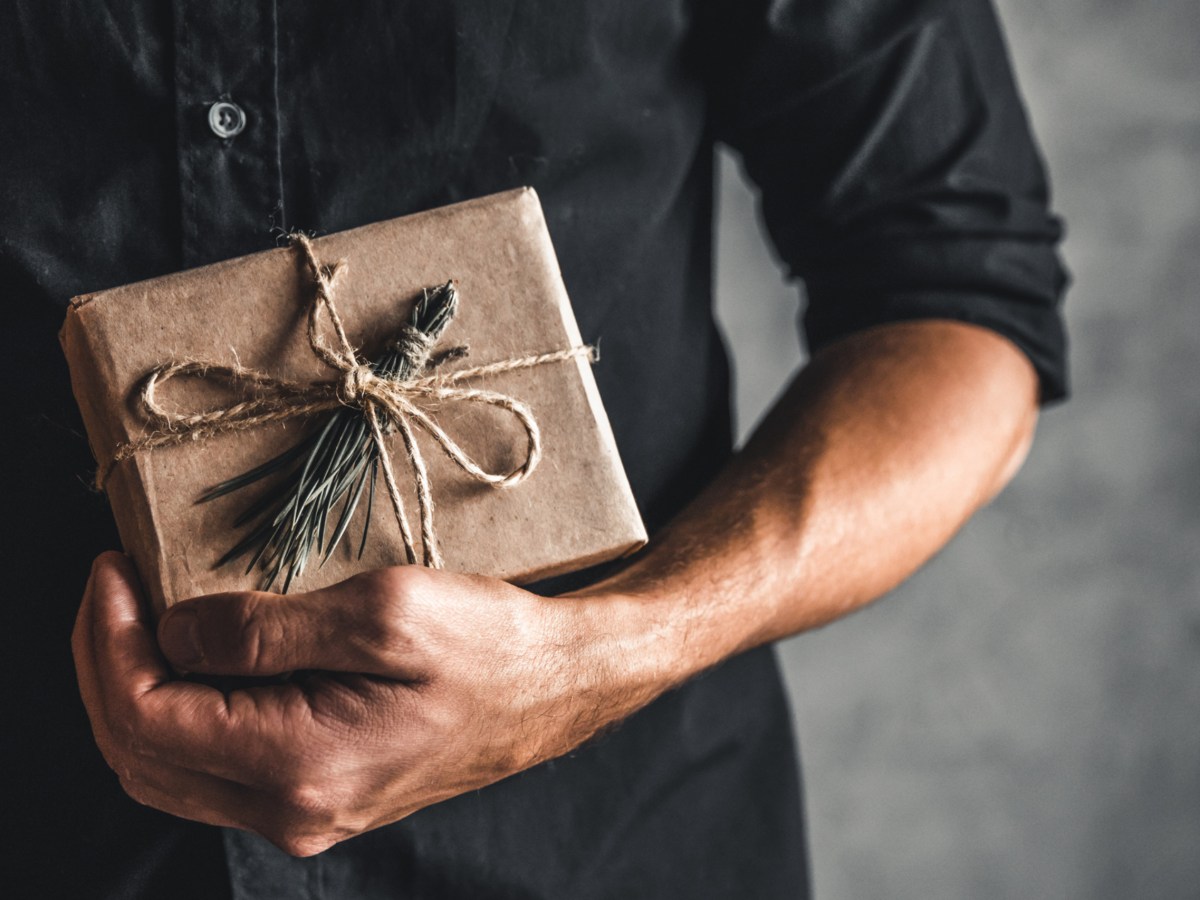 Mann hält ein Weihnachtsgeschenk in der Hand