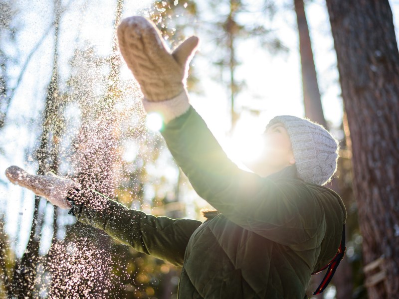 Frau im Winter, die Schnee in die Luft wirft