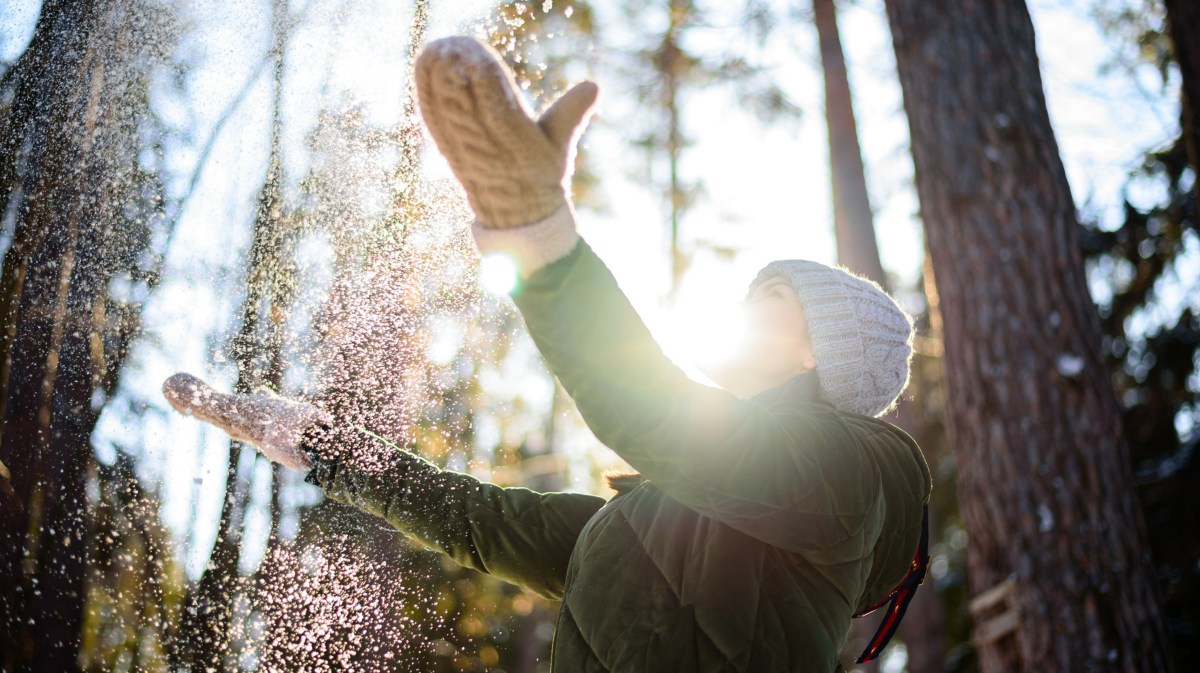 Frau im Winter, die Schnee in die Luft wirft