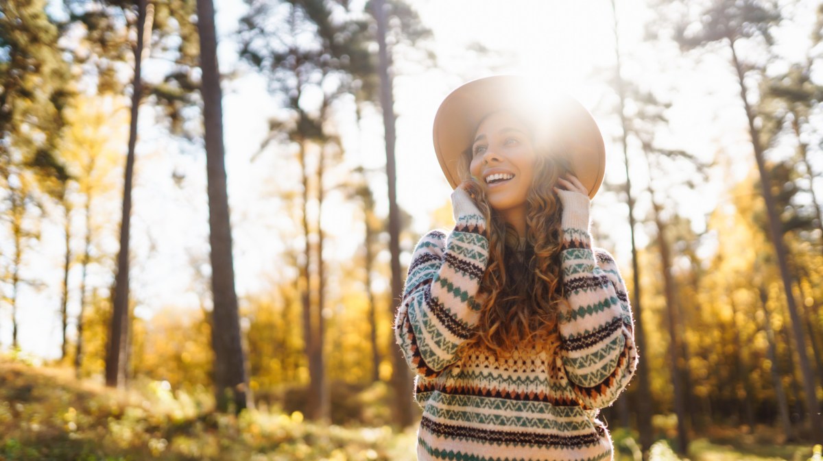 Frau im Wald, die lacht und von der Sonne beleuchtet wird