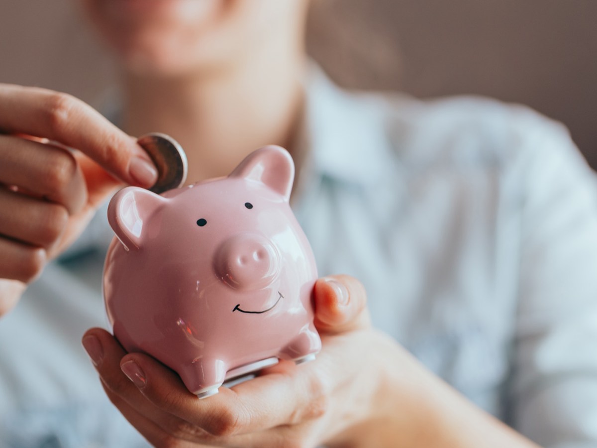 Frau wirft Geld in ein Sparschwein.