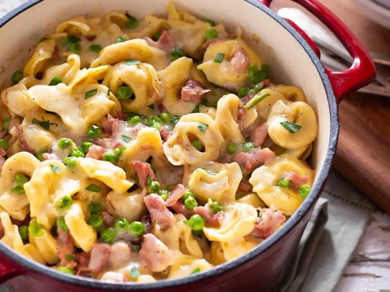 Schinken-Kaese-Tortellini mit Erbsen im Topf.