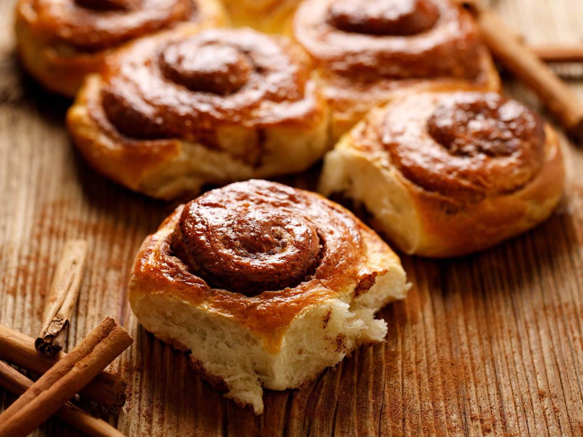 Traditionelle spiralförmige Zimtschnecken auf einem Holztisch, Nahaufnahme