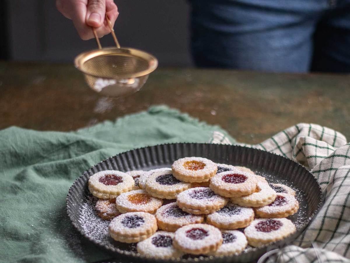 Weihnachten Plätzchen backen, Weihnachtsbäckerei, frisch gebackene Plätzchen mit Puderzucker bestreuen