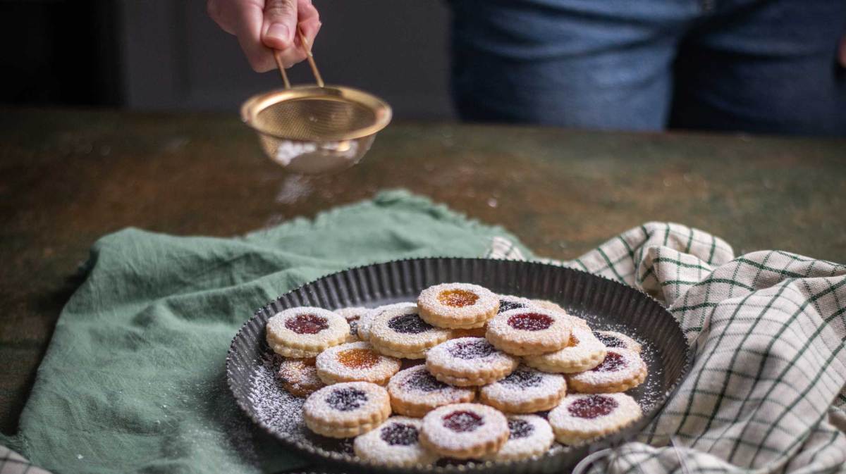 Weihnachten Plätzchen backen, Weihnachtsbäckerei, frisch gebackene Plätzchen mit Puderzucker bestreuen