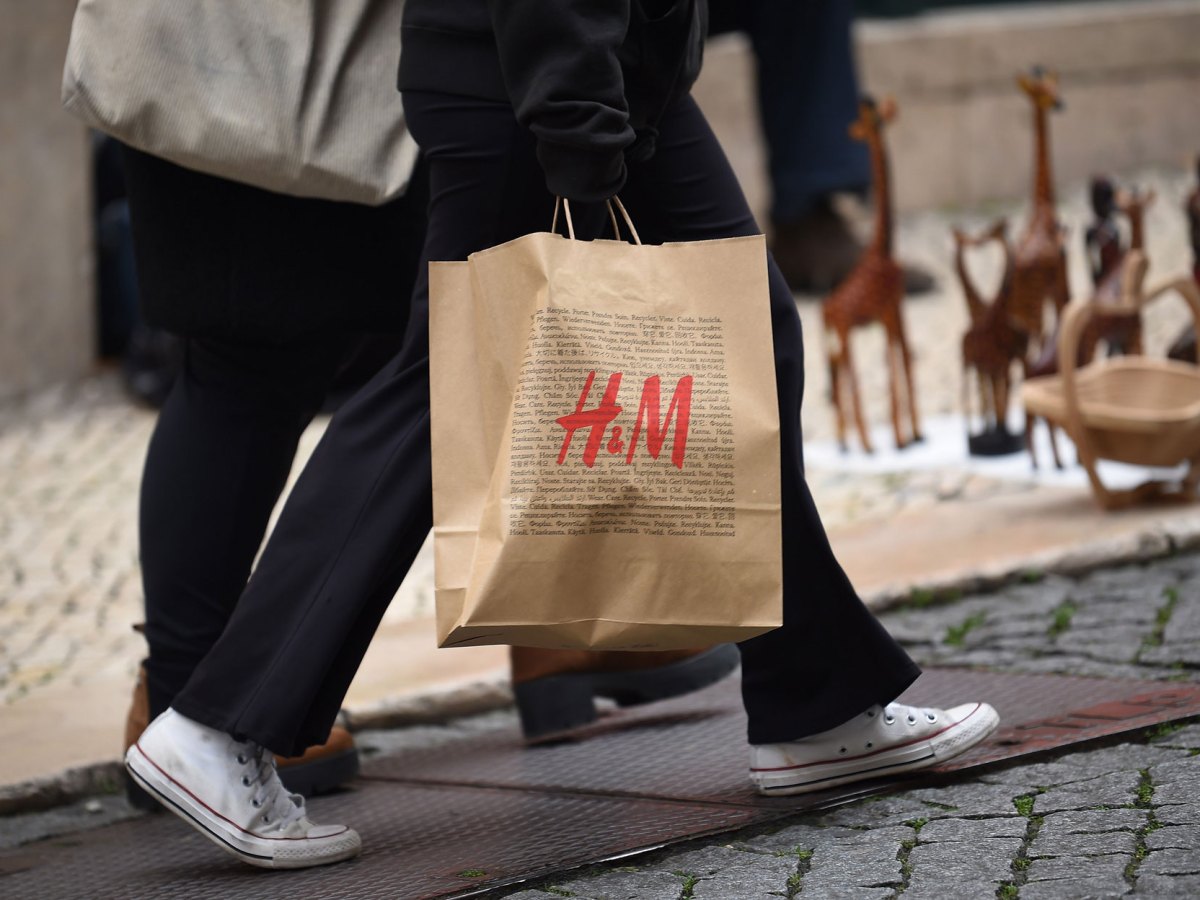 Frau, die gerade bei H&M eingekauft hat und jetzt eine Shoppingtüte trägt.