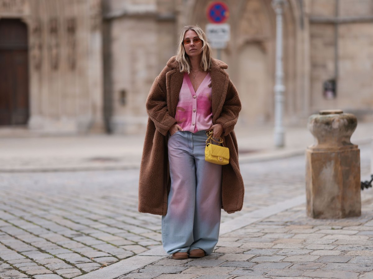 Karin Teigl trägt einen rosa Cardigan und einen braunen Teddymantel zur weiten Jeans.