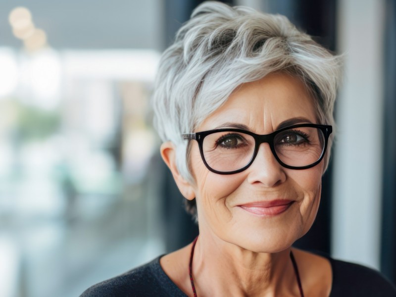 Ältere Frau mit Brille sitzt im Job.