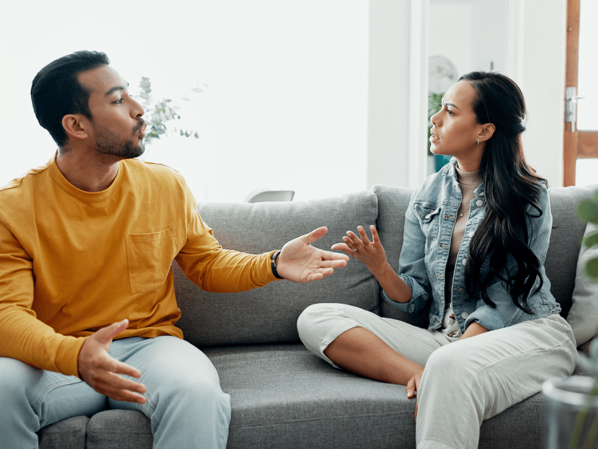 Frau und Mann auf Sofa, die sich gegenseitig Vorwürfe machen