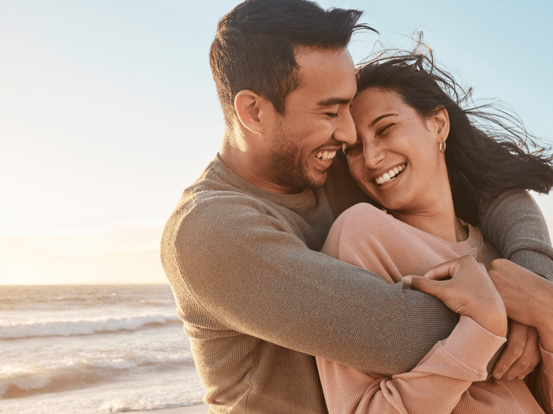 Gl&uuml;ckliches Paar umarmt sich am Strand.
