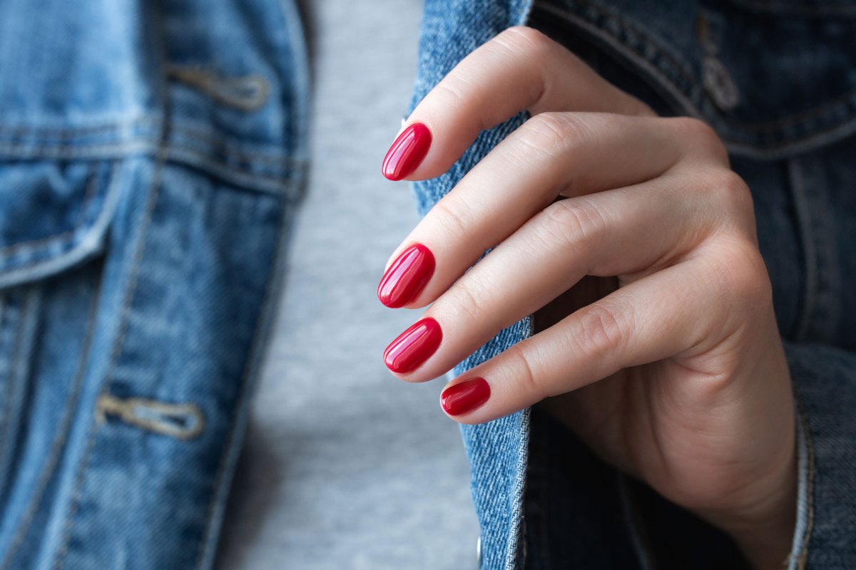 Frau mit perfekten roten Nägeln, die statt Nagellack Nagelfolien verwendet.