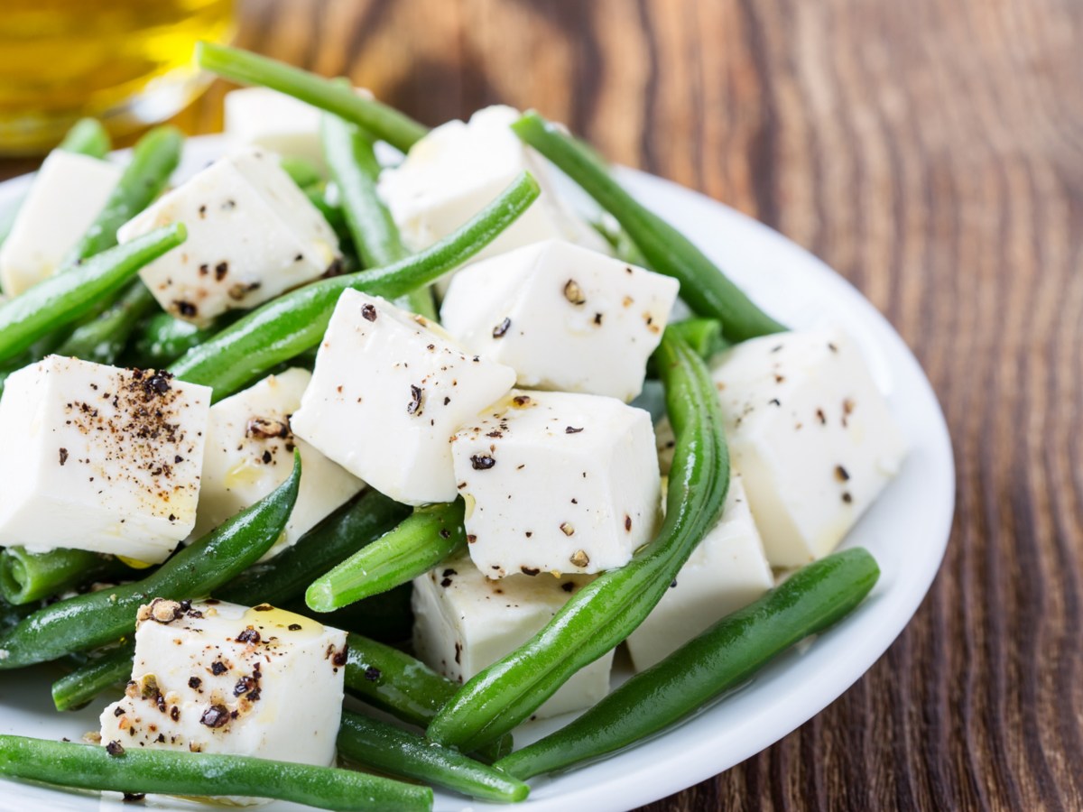 Grüne Bohnen mit Feta auf einem weißen Teller.