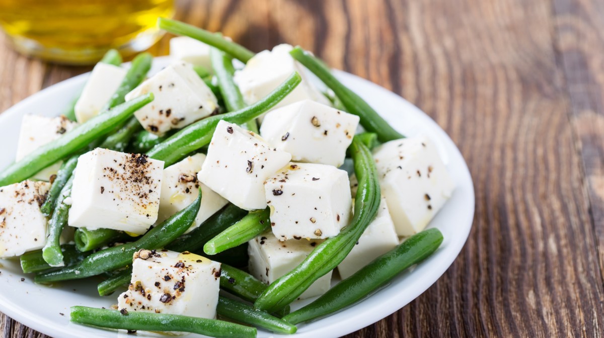 Grüne Bohnen mit Feta auf einem weißen Teller.