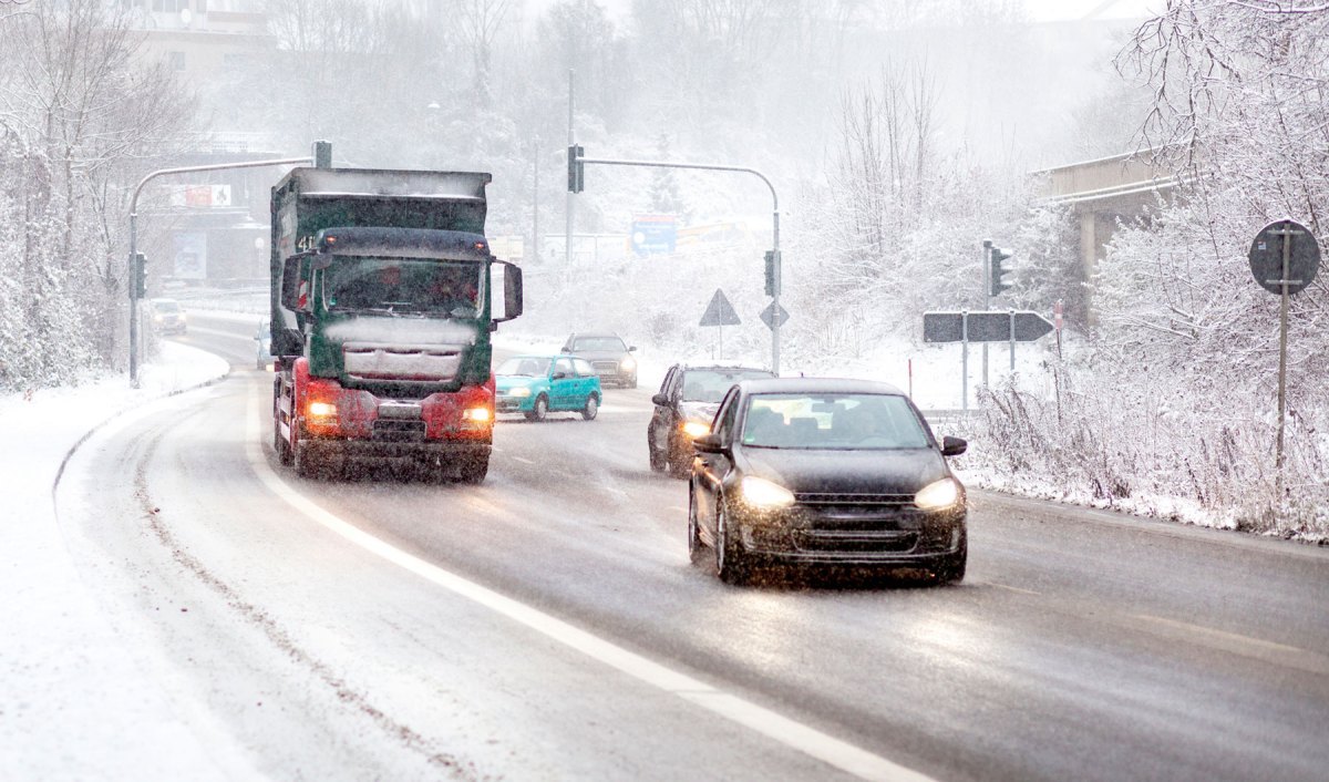 Verschneite Straße darauf Autos und LKW