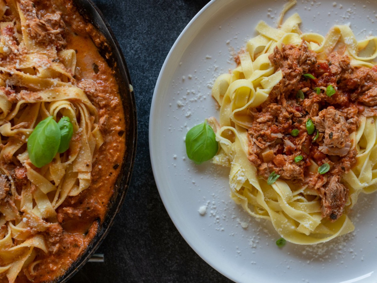 Tagliatelle mit Tomaten-Thunfisch-So&szlig;e auf wei&szlig;em Teller.