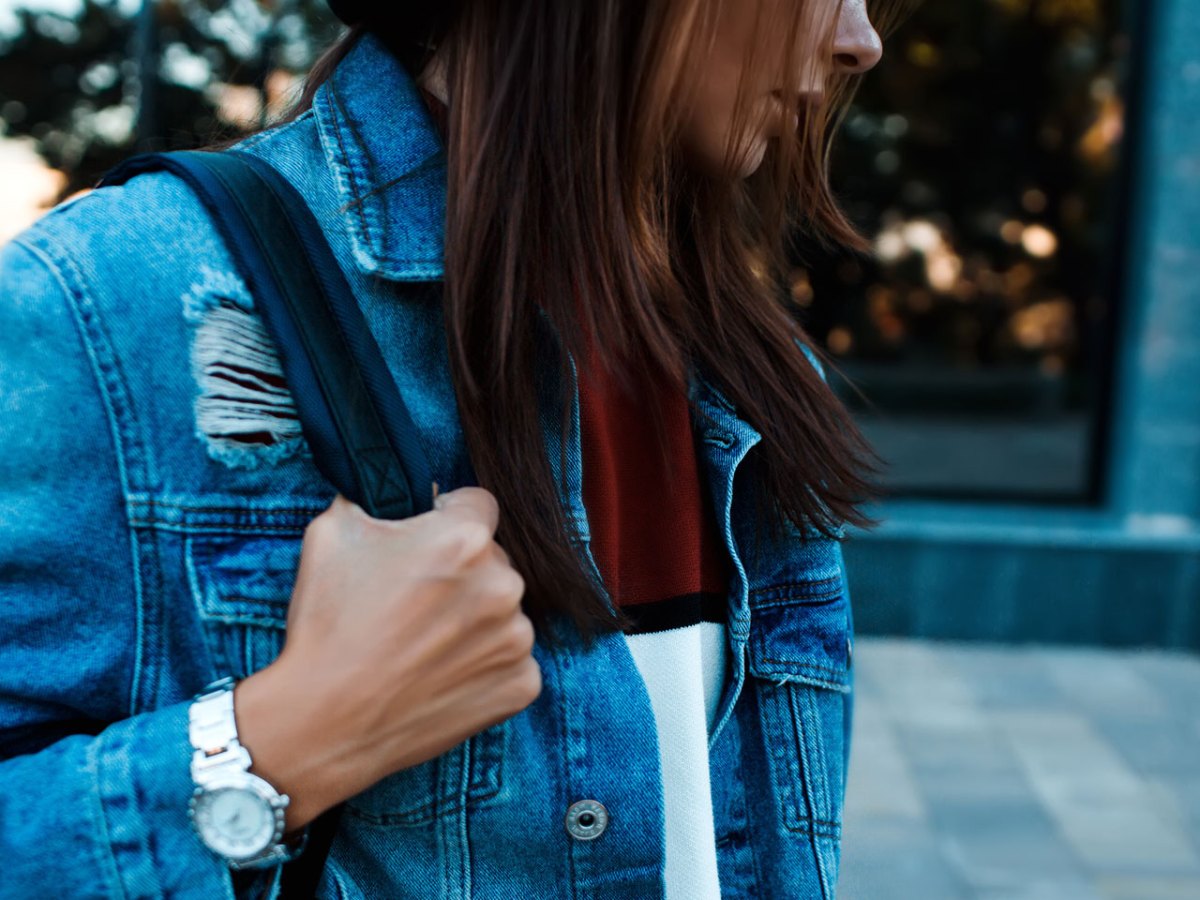 Frau mit Jeansjacke und Tasche schaut ernst