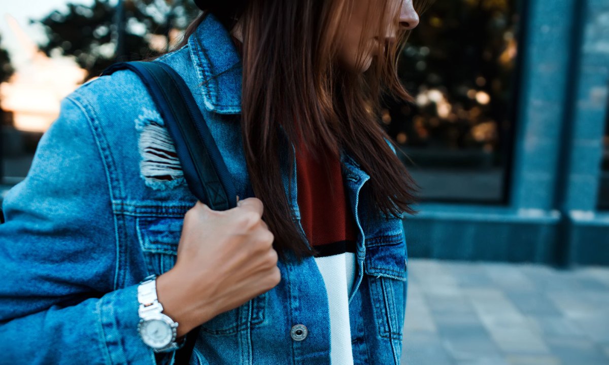 Frau mit Jeansjacke und Tasche schaut ernst