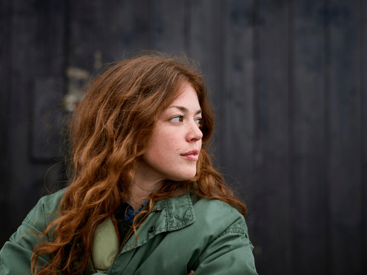 Frau mit roten Haaren blickt ernst zur Seite