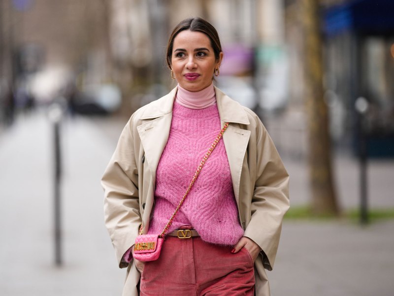 Frau mit rosa Pullover und einem Trenchcoat-Mantel