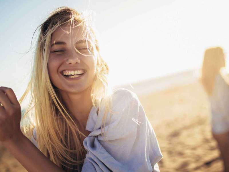 Junge Frau mit langen Haaren ist am Strand mit Freunden.